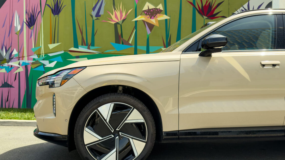 The front half of a Volvo EX90 parked in front of a mural.